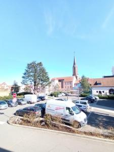 um parque de estacionamento com carros estacionados em frente a uma igreja em petit nid douillet em Ensisheim