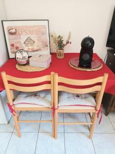une table avec deux chaises et un tissu de table rouge dans l'établissement petit nid douillet, à Ensisheim