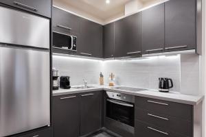 a kitchen with black cabinets and a stainless steel refrigerator at Acropolis Elegant Apartment in Athens