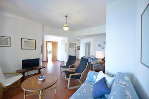 un soggiorno con divano blu e sedie di Villa Le Sprizze a bordo del mare - Goelba a Marciana Marina
