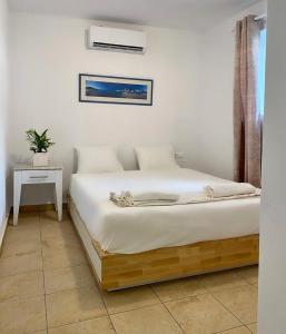 Habitación blanca con cama con mesita de noche y ventana en San Constantine, en Ornos