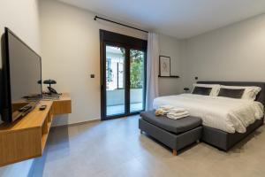 a bedroom with a bed and a tv and a chair at Kaleo Chios Luxury Apartments in Chios