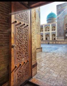une porte ouverte avec une mosquée en arrière-plan dans l'établissement KAMIR Guest House, à Boukhara