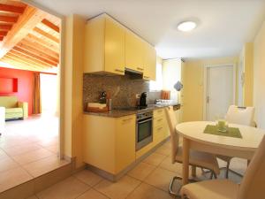 a kitchen with yellow cabinets and a table and a dining room at Depandance Garni Golf in Ascona