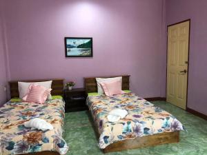 duas camas num quarto com paredes roxas em Green Happy Homestay em Phatthalung