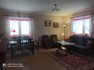 a living room with a couch and a table and chairs at Dom przy lesie in Stare Juchy