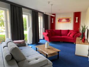 salon z 2 kanapami i czerwoną kanapą w obiekcie Ferienhaus LORINI w mieście Kolkwitz