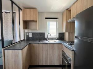 a kitchen with wooden cabinets and a stainless steel refrigerator at Superbe Mobil home 6-8 personnes (57) in Saint-Jean-de-Monts