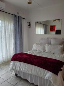 a bedroom with a bed with a red blanket on it at Msongi Guest House in Margate