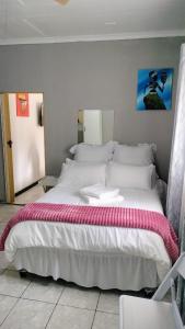 a bedroom with a large bed with white sheets at Msongi Guest House in Margate