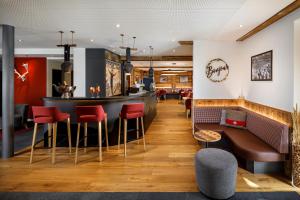 eine Bar in einem Restaurant mit roten Stühlen in der Unterkunft Therme 51° Hotel Physio & Spa in Leukerbad