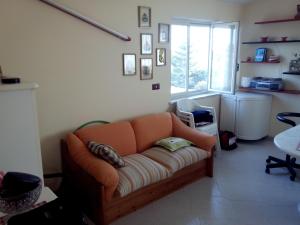 an orange couch in a living room with a window at Appartamento Ognina Siracusa in Ognina