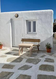a wooden bench sitting in front of a white building at San Constantine II in Ornos