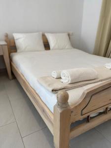 een houten bed met witte lakens en handdoeken erop bij San Constantine II in Ornos