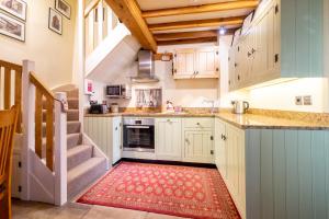 une cuisine avec des placards blancs et un tapis rouge dans l'établissement The Dutch House, à York