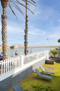 2 chaises de plage et des palmiers à côté d'une clôture blanche dans l'établissement Apartamento Maypa 2 Salitre, à Meloneras