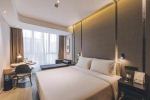 a hotel room with a large bed and a desk at Atour Hotel Jiading Jiangqiao Jiayi Road Subway Station in Fengbang