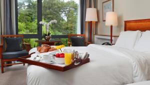 Ballymascanlon Hotel and Golf Resort في دوندالك: صينية طعام على سرير في غرفة الفندق