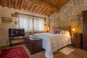 1 dormitorio con 1 cama, TV y pared de piedra en Podere Colombaio - Bucaneve en Radicofani
