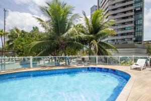 a swimming pool on the roof of a building with palm trees at Edif Flat Beira Mar in Recife