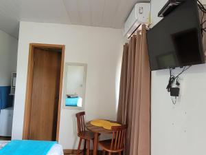 a room with a table and a television and a bed at Batera House Noronha in Fernando de Noronha