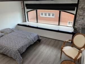 een slaapkamer met een bed, een raam en een stoel bij Arts Urban duplex Loft & RoofTop in Roubaix