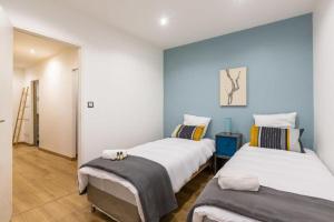 two beds in a room with blue walls at EasyLodge - Appartement 3 chambres Bordeaux in Bordeaux