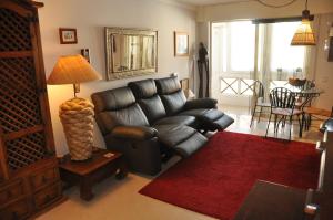 a living room with a black leather couch and a red rug at Apart Lisbon Pool Metro Garage in Lisbon