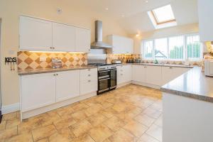 a kitchen with white cabinets and a stove top oven at Anrose House in Llandrillo-yn-Rhôs