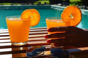 two glasses of orange juice and a persons hand on a table at la matilda in Santa Rosa de Calamuchita