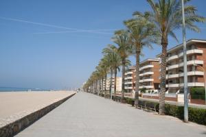 a sidewalk next to a beach with palm trees and buildings at R140 Manila Resort Jardin in Calafell