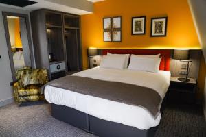 a bedroom with a large bed with an orange wall at Great North Hotel in Newcastle upon Tyne