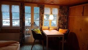 Habitación con mesa, sillas y ventana en bei der Arve 4 Bett Wohnung en Grindelwald