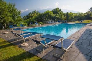 a pool with blue chairs and a table and benches at Residenza Viramonte - Casa Bianca, Wohnung 15 in Vira