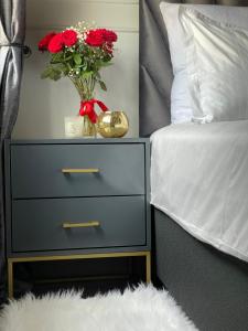 a nightstand with a vase of red roses in a bedroom at Little Heaven in Johannesburg
