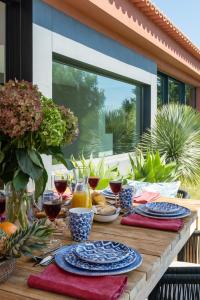 uma mesa de madeira com pratos de comida e copos de vinho em Garden Seaside Villa by CadenzaLux em Cascais