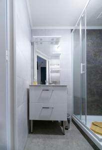 La salle de bains blanche est pourvue d'un lavabo et d'un miroir. dans l'établissement L'Annexe Gannat - Appartements en centre ville, à Gannat