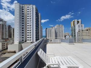 un balcón con 2 sillas blancas en la parte superior de un edificio en Lindo apto Balneário Camboriú 2 quartos Av BRASIL, en Balneário Camboriú