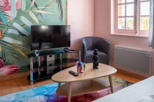 a living room with a tv and a coffee table at Le Rose poudré - Spacieux et lumineux- Hypercentre in Lisle-sur-Tarn