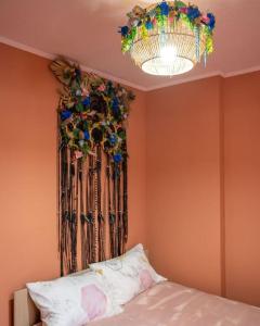 Cette chambre comprend un lit et un lustre orné de fleurs sur le mur. dans l'établissement Le Rose poudré - Spacieux et lumineux- Hypercentre, à Lisle-sur-Tarn