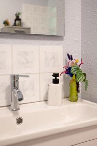 La salle de bains est pourvue d'un lavabo et d'un vase de fleurs. dans l'établissement Le Rose poudré - Spacieux et lumineux- Hypercentre, à Lisle-sur-Tarn