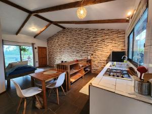 cocina con pared de ladrillo, mesa y sillas en Cabañas Kainga, en Hanga Roa