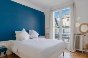 - une chambre avec un lit blanc et un mur bleu dans l'établissement Courcelles Design Duplex, à Paris