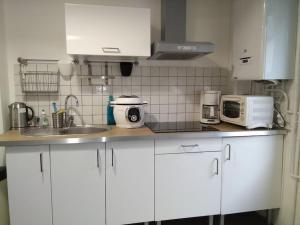 a kitchen with white cabinets and a sink and a microwave at Maison de Pêcheur La Gorge Bleue in Saint-Valéry-sur-Somme