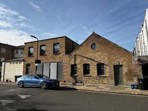 a blue car parked in front of a brick building at Sienna's 2 - bedroom apartment, London, N1. in London