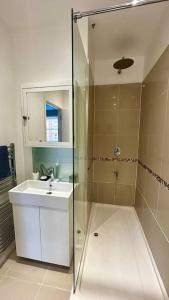y baño con ducha acristalada y lavamanos. en Sienna's 2 - bedroom apartment, London, N1., en Londres