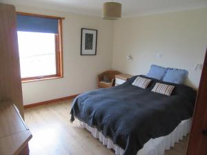 a bedroom with a bed with blue sheets and a window at Osprey, Longhouse Cottages in Rosemarkie