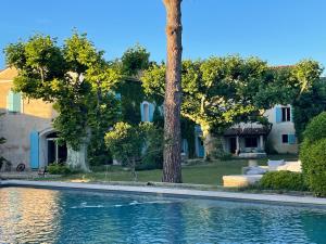a swimming pool in front of a house with trees at Le Mas des Perrines Maison d’Hôtes in Pernes-les-Fontaines