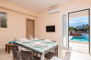 Astarte Villas - Ocean Pool Villa في تسيليفي: غرفة طعام مع طاولة وكراسي وتلفزيون