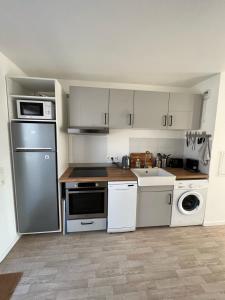 uma pequena cozinha com electrodomésticos brancos e um lavatório em Modern and bright apartment near Paris em La Courneuve